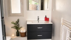 A bathroom with a white sink, black vanity, a mirror, a green bath mat, and a white towel rack. - Quiet house in Seignosse. Enclosed patio and parking  (Seignosse)