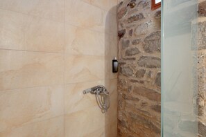A shower with a handheld showerhead, a glass door, and a stone wall. - Apartment 'Castle Rizaraki 204' with Sea View, Wi-Fi and Air Conditioning (Γύθειο)