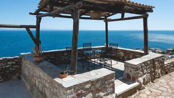 Une pergola en bois avec une table et des chaises, donnant sur la mer.