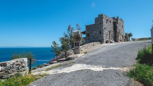 Un edificio in pietra con una strada lastricata che vi conduce, affacciato su uno specchio d'acqua.