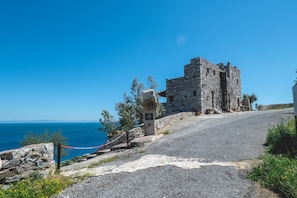 Un edifici de pedra amb un camí pavimentat que hi convergeix, amb vistes a una massa d'aigua.