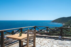 A wooden table with a potted plant, a chair, and a stone floor. - Apartment 'Castle Rizaraki 204' with Sea View, Wi-Fi and Air Conditioning (Γύθειο)