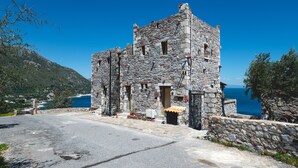 Un edificio in pietra dal sapore rustico, con un ingresso lastricato e vista sul mare.
