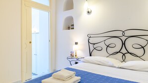 Ein Hotelzimmer mit Bett, Nachttisch, Lampe und einer Tür, die auf einen Balkon führt.