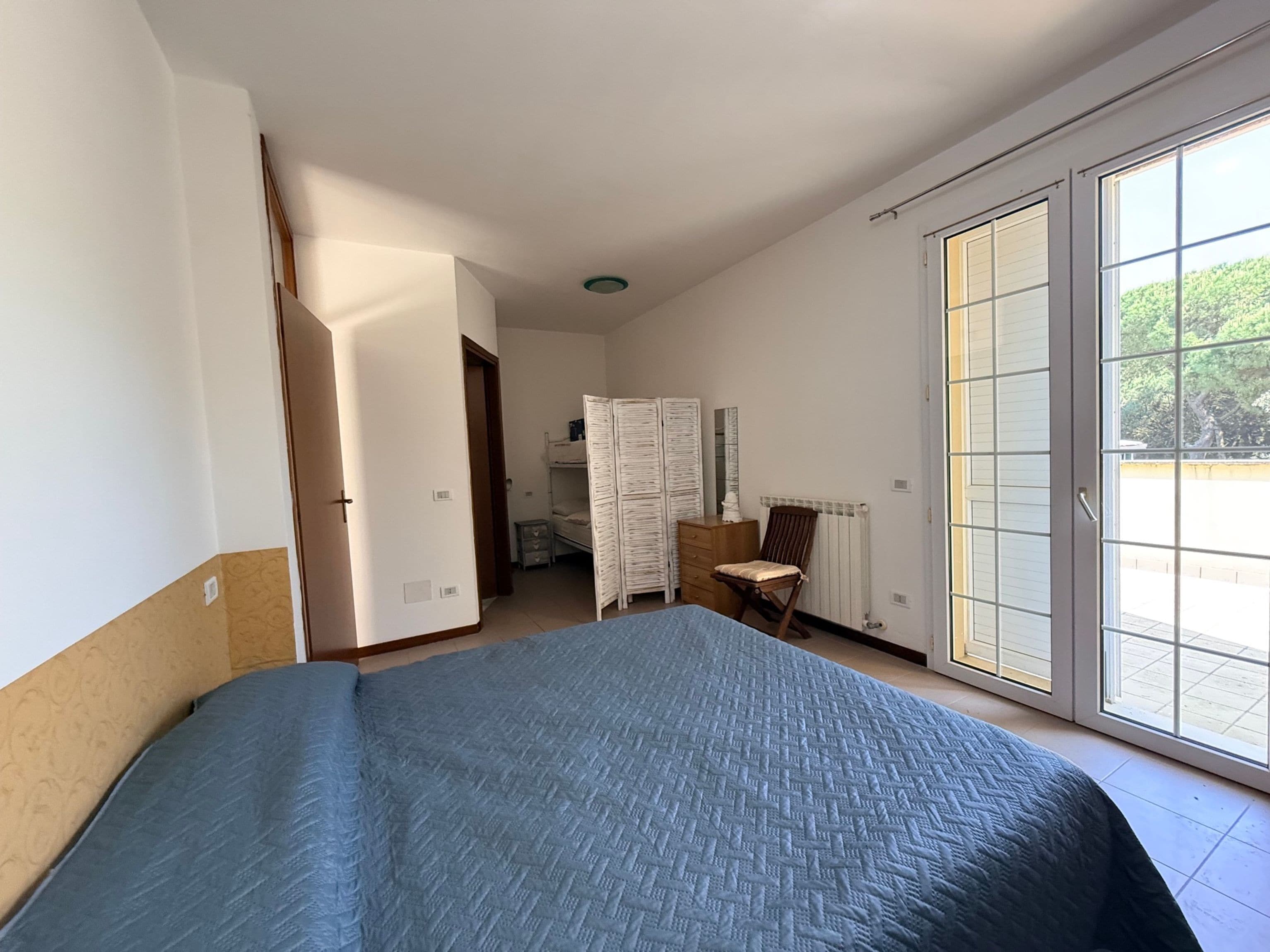 Quarto com uma cama grande, uma cadeira, uma cômoda e um guarda-roupa.