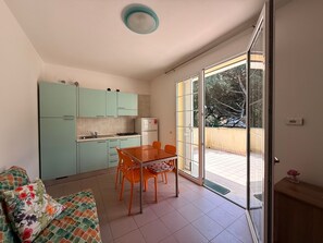 Eine kompakte Küche mit Esstisch und Stühlen, einer Couch und einer Glastür zu einem Balkon.