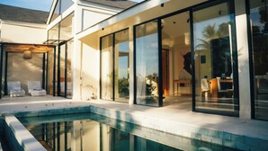 Ett modernt hus med en swimmingpool, stora glasfönster och en uteplats.