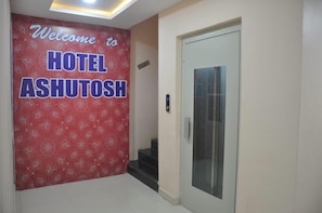 A hotel entrance with a red patterned wall and a sign reading 'Welcome to HOTEL ASHUTOSH.' - HOTEL ASHUTOSH Mandsaur (Mandsaur)