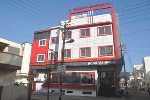 Ein mehrstöckiges Hotel mit roter und weißer Fassade, zahlreichen Fenstern und einem Schild, das es als Hotel kennzeichnet.