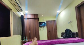 A bedroom with a bed, a wardrobe, a television, and a desk with a chair. - HOTEL ASHUTOSH Mandsaur (Mandsaur)