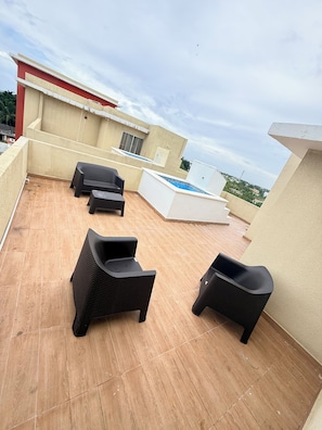 Eine Dachterrasse mit Gartenmöbeln, einem Pool und Blick auf die Stadt.