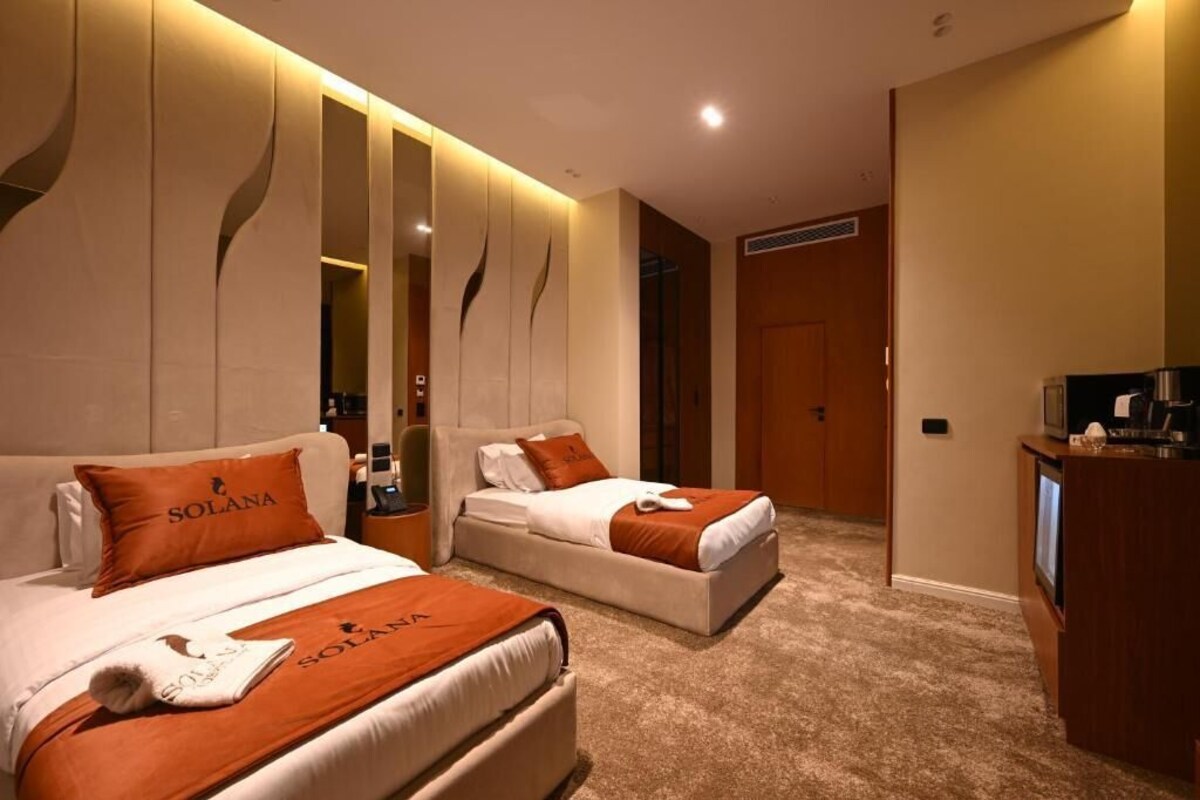 Ein Hotelzimmer mit zwei Betten, einem Fernseher und einer Minibar.