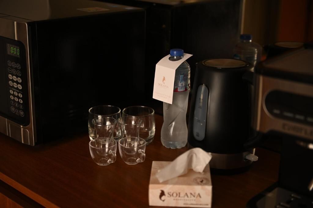Un four à micro-ondes, une bouteille d’eau, une machine à café et quatre verres sur une surface en bois.