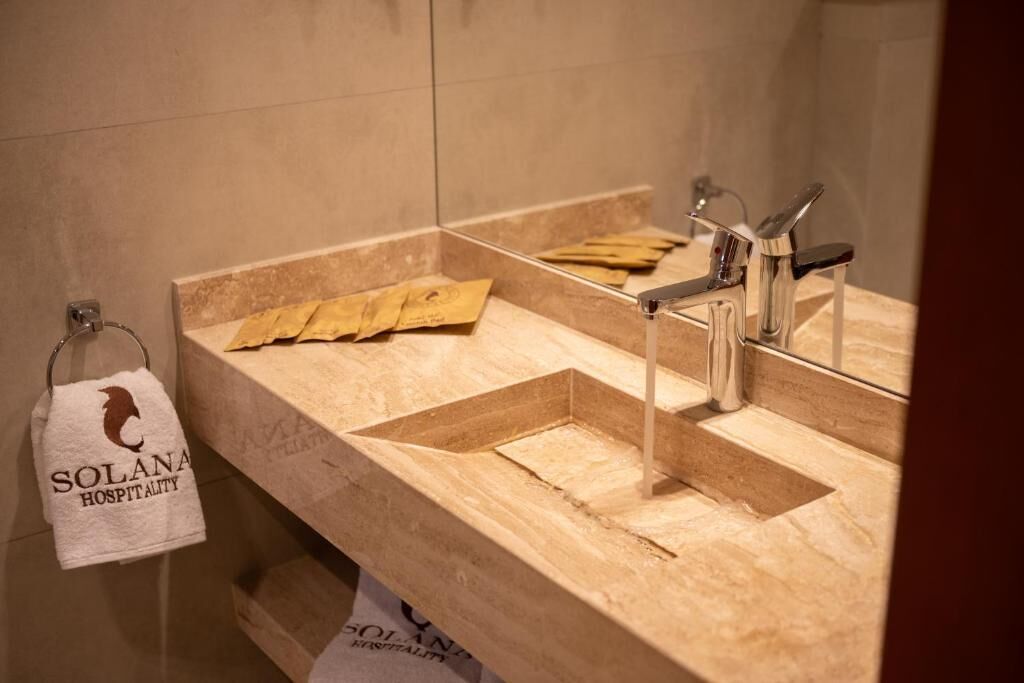 Un baño con encimera color crema, lavamanos y un perchero con una toalla.