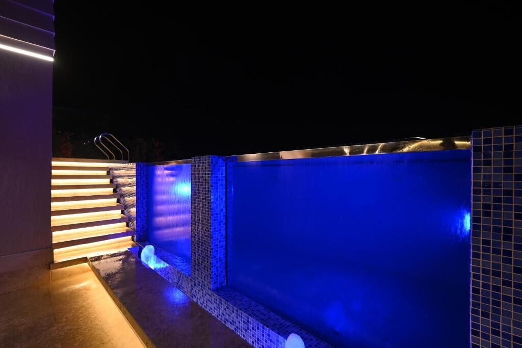 Una piscina con iluminación azul y un muro con azulejos.