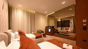 Ein Hotelzimmer mit zwei Betten, einem Schreibtisch, einem Stuhl, einem Spiegel und einem großen Fenster mit Vorhängen.