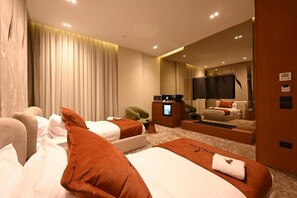 Habitación de hotel con dos camas, un escritorio, una silla, un espejo y un ventanal grande con cortinas.