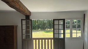 Ein Schlafzimmer mit einem großen Bett, einer hölzernen Kommode und einem Balkon mit Blick auf Grünflächen.