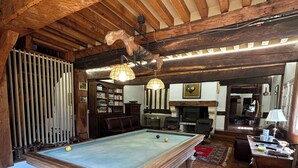 Ein Billardtisch in einem Raum mit Holzbalken, Kamin und einer Billardkugel.