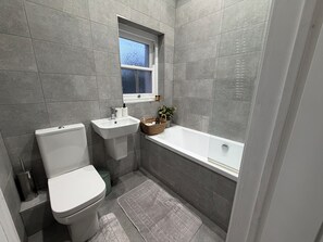 Une salle de bain avec des toilettes, un lavabo et une baignoire.
