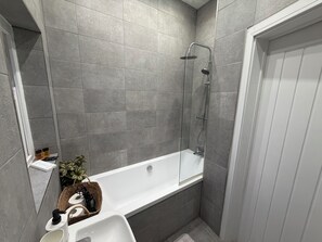 A modern bathroom with a shower, a bathtub, and a sink.