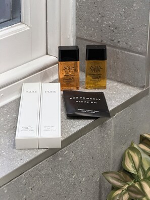 Une étagère de salle de bain avec deux bouteilles de produits Aqua Viva, une trousse de soins dentaires et une trousse de toilette.