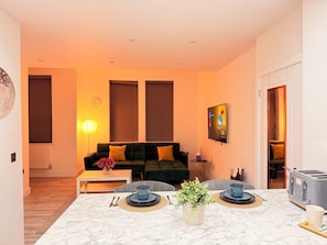 Un salon moderne avec un canapé, une table basse et un téléviseur fixé au mur.