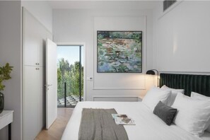 A modern bedroom with a bed, a painting, a nightstand, and a view of the outdoors. - Villa Valens Residence (Tinjan)