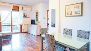 A modern living room with a dining area, large windows, a television, and a framed picture on the wall. - Roman Urban Stay (Roma)