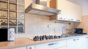 A modern kitchen with a gas stove, stainless steel sink, and white cabinets. - Roman Urban Stay (Roma)
