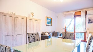 A room with a glass-top table, wooden cabinets, a sofa, and a window with curtains. - Roman Urban Stay (Roma)