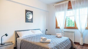 A neatly made bed with a quilted blanket, a bedside lamp, and a framed picture on the wall. - Roman Urban Stay (Roma)