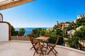 A balcony with a table and chairs, overlooking a coastal town with buildings and palm trees. - Holiday Home 'Mía' with Sea View, Wi-Fi and Air Conditioning (Xàbia)