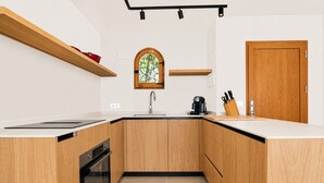 Una cocina con armarios de madera, horno empotrado, ventana con vistas y una puerta con un juego de cuchillos sobre la encimera.