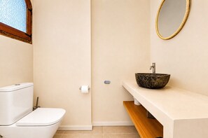 A bathroom with a toilet, a sink with a stone basin, and a mirror on the wall.