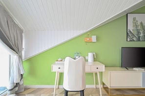 A room with a desk, chair, television, and a green wall. - Encounter Villa Art  Garden Homestay (Qingdao)
