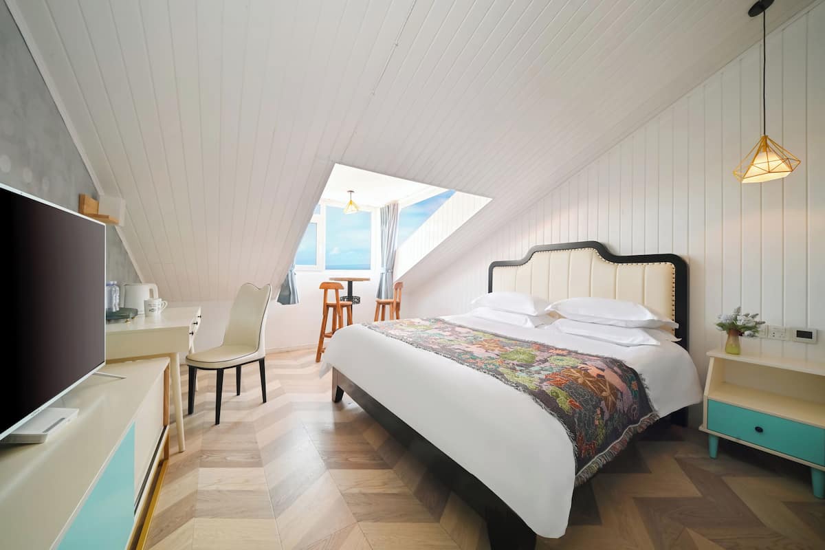 A bedroom with a bed, a desk, a chair, and a TV.