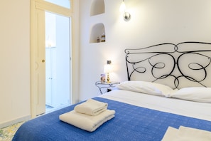 Ein Hotelzimmer mit Bett, Nachttisch mit Lampe und einer Tür zu einem Außenbereich.