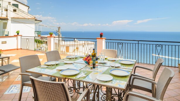 En terrasse med et spisebord, der vender ud mod et vandareal.