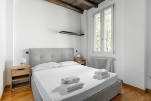 A bedroom with a bed, two bedside tables, a window, and a radiator. - Casa Centotrecento by Wonderful Italy (Bologna)