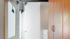 A hallway with wooden flooring, a white wall, and a wooden wardrobe with two doors. - Casa Centotrecento by Wonderful Italy (Bologna)