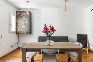 A dining area with a wooden table, four chairs, a vase with flowers, a bench, and a wall with a leaf-patterned wallpaper. - Casa Centotrecento by Wonderful Italy (Bologna)