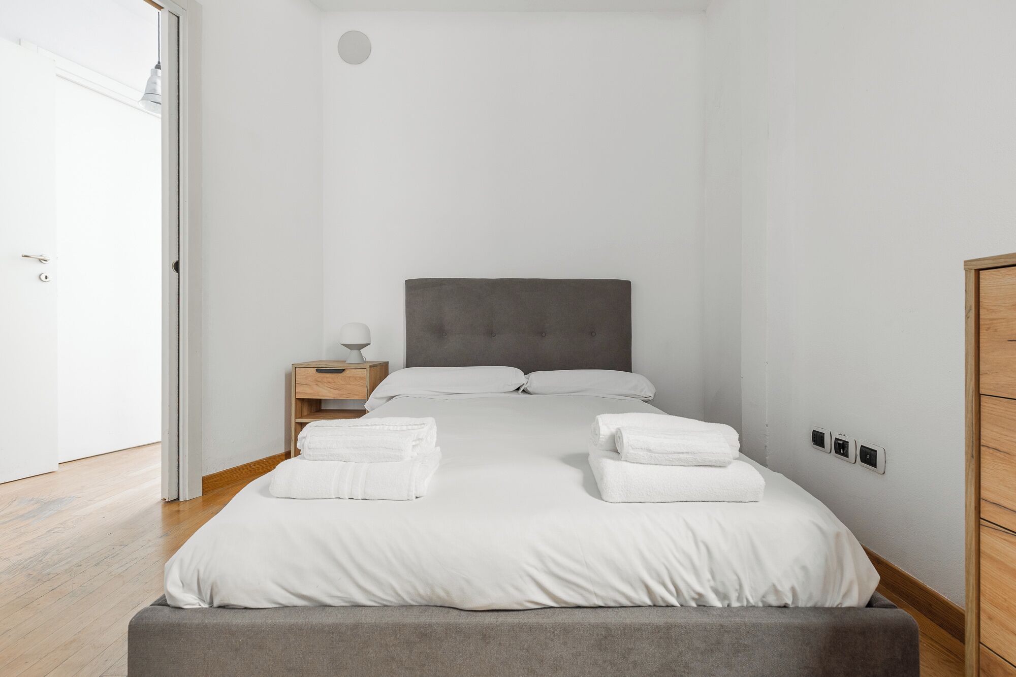 Une chambre à coucher avec un lit, une table de chevet et une armoire.