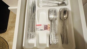 Een lade met een set bestek, waaronder een vork, mes en lepel, alles verpakt in plastic.
