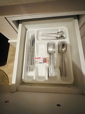 Un tiroir contenant un ensemble de couverts, notamment une fourchette, un couteau et une cuillère, le tout emball é dans du plastique.