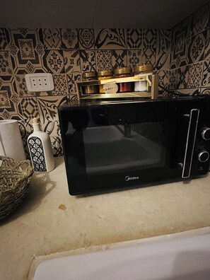 A black Midea microwave oven on a kitchen counter with patterned tiles, a basket, and a white appliance. - Bohemian Bed&Breakfast house with AC l 2 minutes from airport (Tunis)