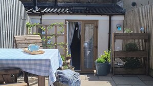 A patio with a checkered tablecloth, a patterned rug, and a wooden bench. - The Sails – Romantic Retreat for Two, Cosy Light-Filled House (Leek)