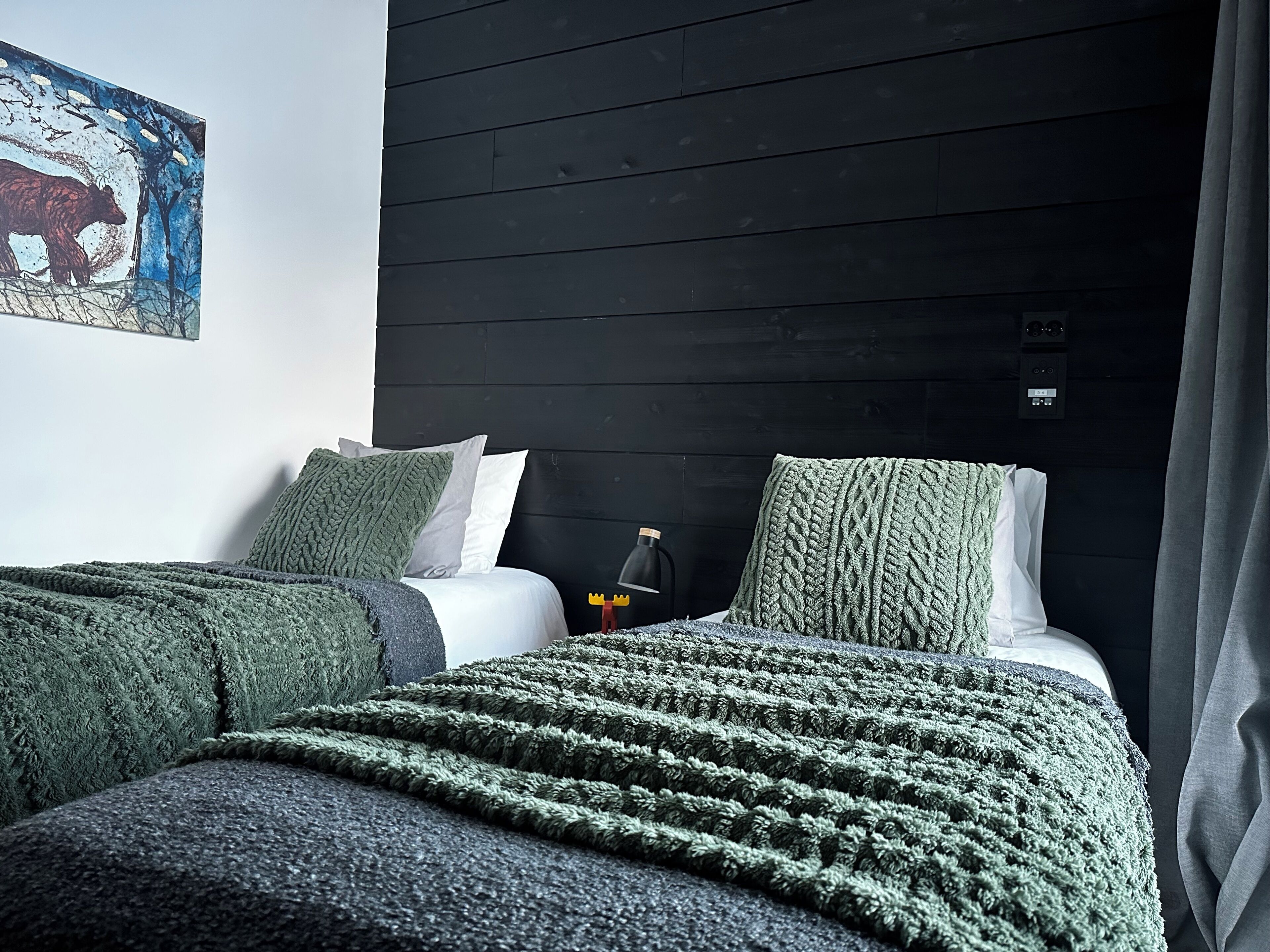 Une pièce comprenant un lit, une table de chevet, une lampe et un tableau accroché au mur.