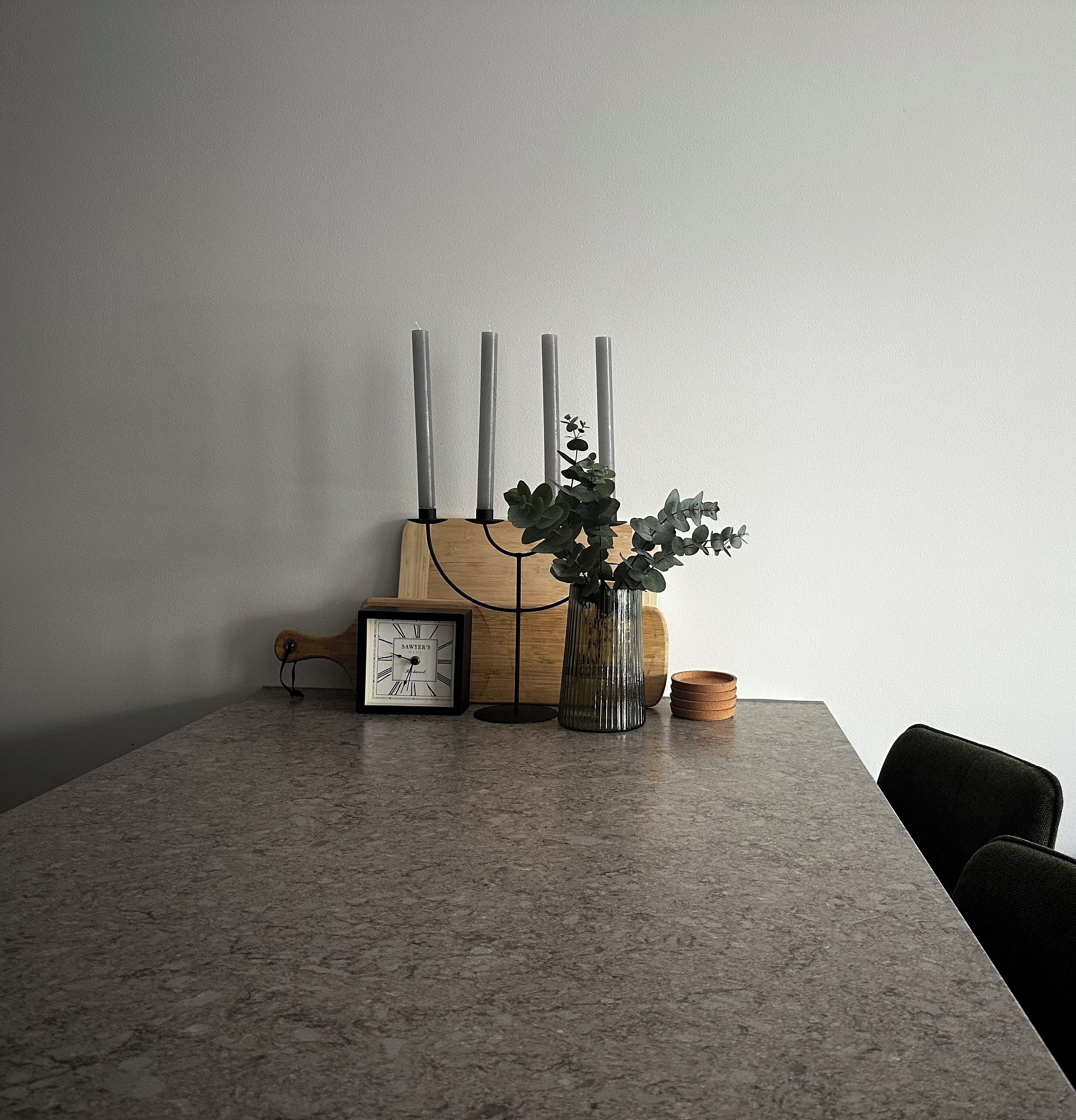 Une table avec une horloge, des bougies et une plante.