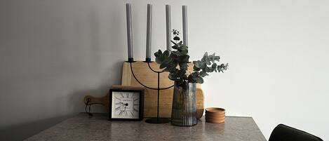 Une table avec une horloge, des bougies et une plante.
